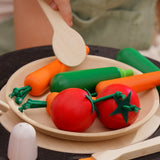 The Plan Toys Vegetable Produce Set with wooden Carrots, Courgettes & Tomatoes play food shown on a wooden toy plate in a play kitchen.