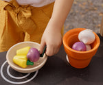 Plan Toys wooden play food Produce Set containing Radish, Garlic & Yellow Peppers. The produce has been placed in a wooden pot and a wooden bowl.