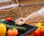 A child placing a toy wooden onion from the Plan Toys Vegetable Produce Set on a metal grill.