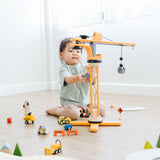 A child sitting on the floor playing with the PlanToys PlanWorld Crane Set.