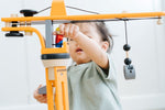 A close up of a child playing with the PlanToys PlanWorld Crane Set.