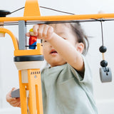 A close up of a child playing with the PlanToys PlanWorld Crane Set.