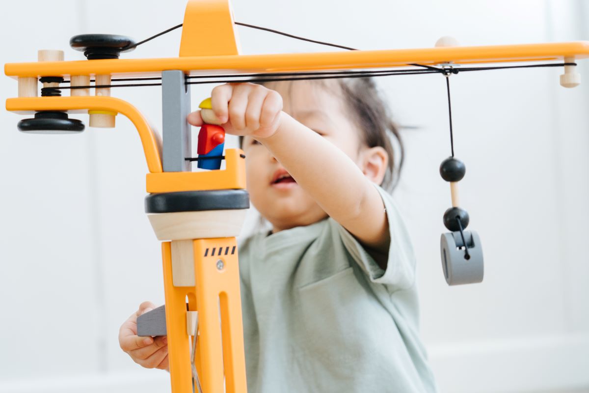 A close up of a child playing with the PlanToys PlanWorld Crane Set.