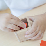 A close up of a child's hands playing with the PlanToys Fractions Cubes.