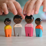 The PlanToys PlanWorld Black Skin, Black Hair Family stood up, a child's hand can be seen reaching for them.