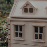 A close up of the corner of the PlanToys Victorian Dolls House in a forest.
