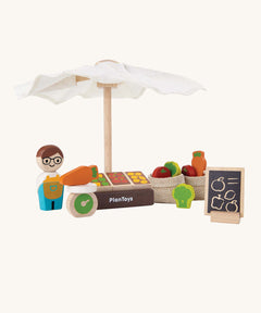 The Plan Toys wooden market toy set, with a peg doll figure and a wooden fruits and veg stand.