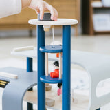 A close up of a child's hand playing with the PlanToys PlanWorld Central Station Wooden toy. They are operating the lift part.