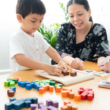 A child and an adult playing with the PlanToys 100 Rainbow Counting Cubes.