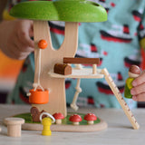 A close up of the PlanToys PlanWorld Tree House being played with by a child. The child's hand can be seen holding onto the little wooden doll figure.