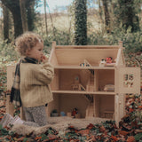 A child playing with the PlanToys Victorian Dolls House in a forest.