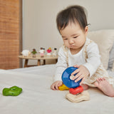 A baby playing with the Plan Toys Wave Stacker - a wooden stacking rainbow baby toy.