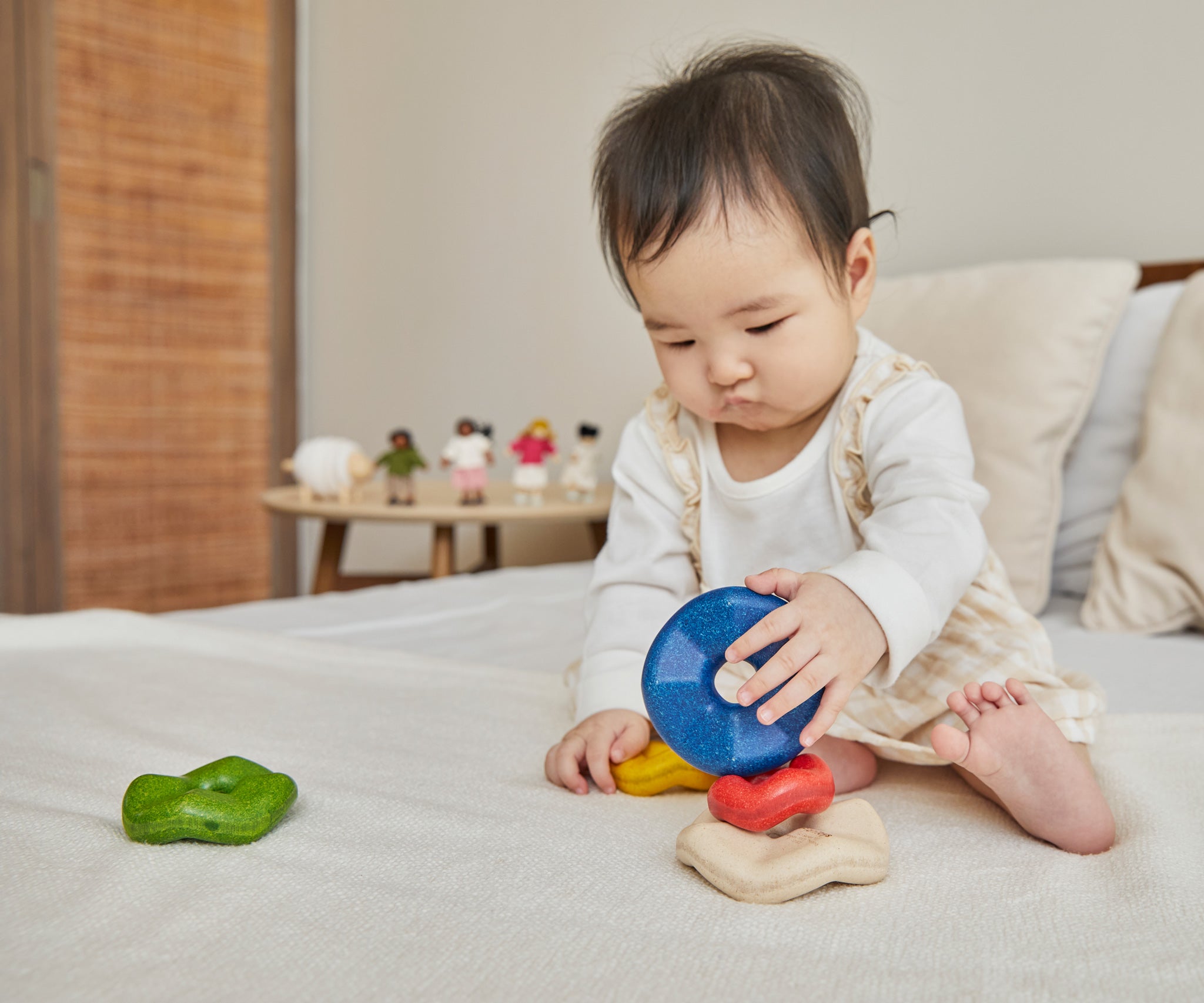 A baby playing with the Plan Toys Wave Stacker - a wooden stacking rainbow baby toy.