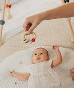 A close up of an adult's hand holding up a PlanToys Beads Rattle in a High Contrast colourway above a baby. 
PlanToys range of toys are made from sustainably sourced rubberwood, we're proud stockists of PlanToys here at Babipur.