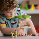 The PlanToys PlanWorld Tree House being played with by a child. The child's hand can be seen holding on to one of the little wooden toadstools.