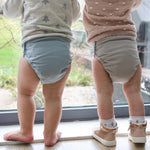 Two babies wearing The Close Pop-In reusable cloth nappies with adjustable velcro, in pastel colours