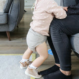 A baby wearing The Close Pop-In reusable cloth nappy with adjustable velcro, in Cloud Grey.