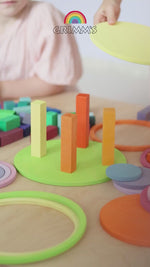 A video of children using the Grimm's concentric circles to play in all sorts of ways. First they stack a tower with wooden building blocks, then they spin the disc circles on the table, then they create steps and run the circles down.