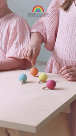 A video of children spinning the Grimm's pastel rainbow traditional wooden spinning tops.
