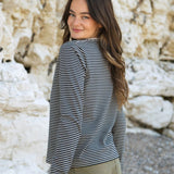 A side view of the Rapanui striped  t-shirt in solent oat and navy stripes design worn by a woman. Showing the oat and navy stripe design on organic cotton fabric