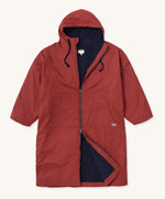 Rapanui changing robe in rust colour. A organic cotton long length changing robe with PFC-free water-resistant coating and a navy towelling lining. Features a two way zip and a hood with pouch pockets.