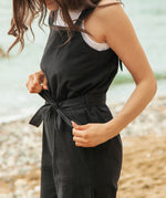 A close up of the black Rapanui jumpsuit showing the black belt tie and pocket detail on organic cotton fabric