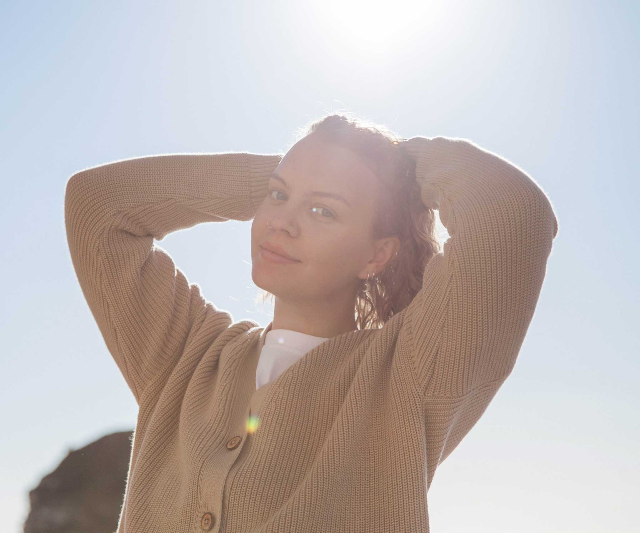 A woman wearing the Rapanui Brook Organic Cotton Women's Knitted Cardigan.