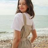 A close up of the driftwood Rapanui jumpsuit showing the matching belt tie and shoulder strap detail with holes for different size adjustments  on organic cotton fabric.