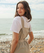 A close up of the driftwood Rapanui jumpsuit showing the matching belt tie and shoulder strap detail with holes for different size adjustments  on organic cotton fabric.