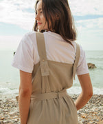 A close up of the driftwood Rapanui jumpsuit showing the shoulder strap detail with holes for different size adjustments  on organic cotton fabric.