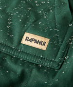A close up of the brand patch stitched on the pocket of the Rapanui chanigng rope showing the effect of the PVC free water resisting coating on evergreen organic cotton fabric