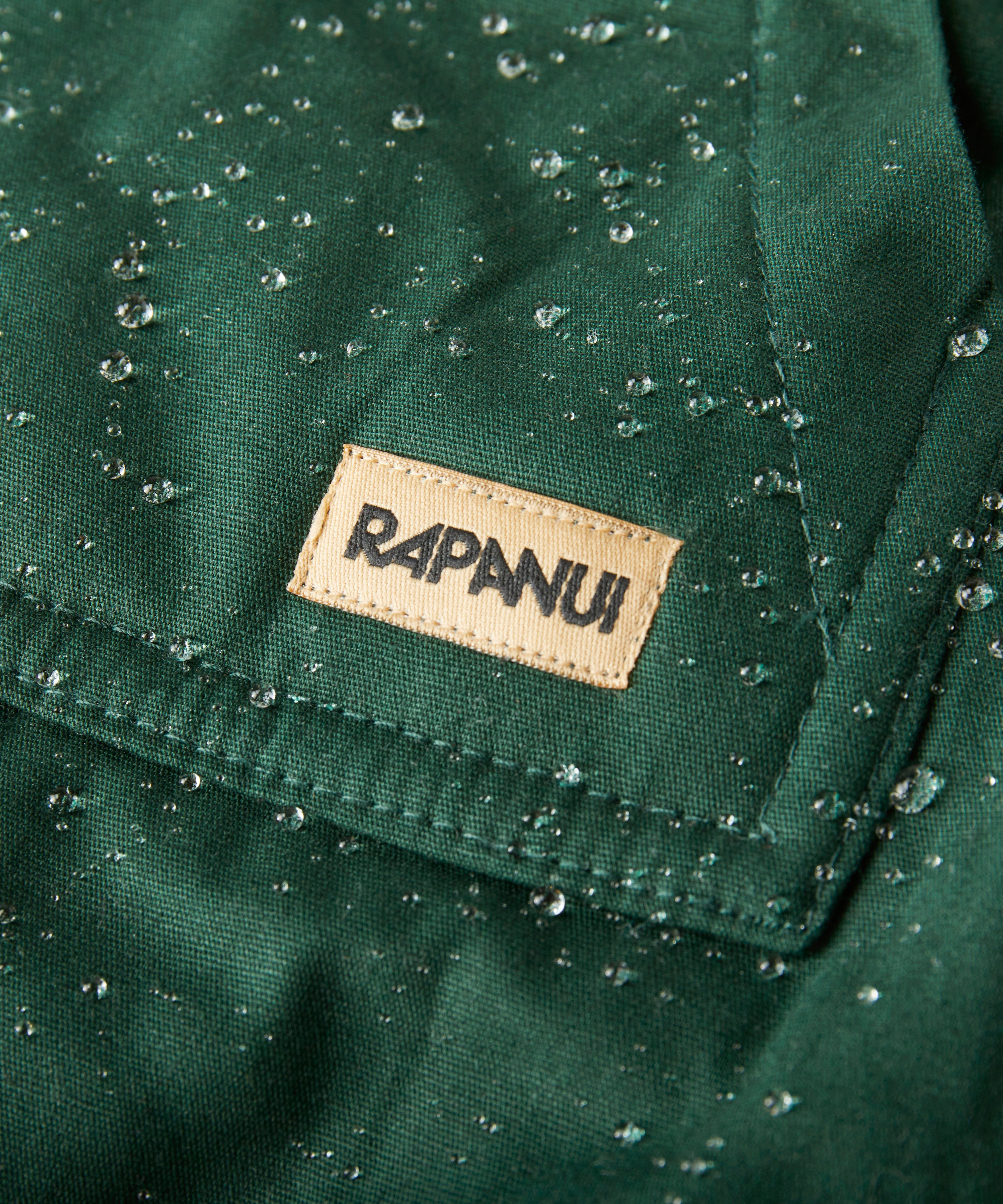 A close up of the brand patch stitched on the pocket of the Rapanui chanigng rope showing the effect of the PVC free water resisting coating on evergreen organic cotton fabric