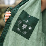 A close up of the inside lining of the Rapanui changing robe in evergreen colour showing the towelling detail on the inside and zip detail. Features a pocket on the inside with washing and drying instructions.