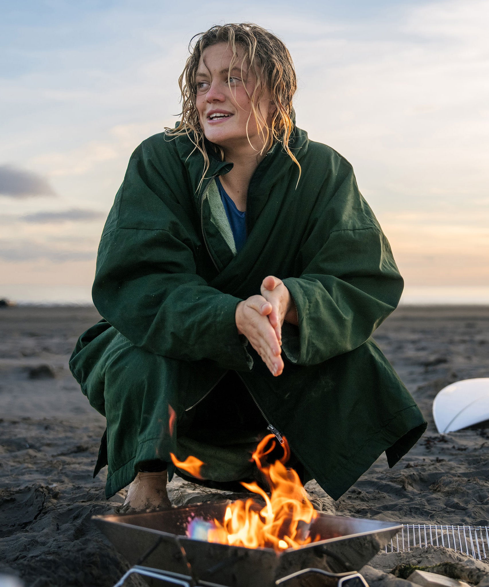 A woman on the beach wearing the Rapanui changing robe in evergreen colour. A organic cotton long length changing robe with PFC-free water-resistant coating