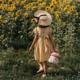 Picture of a child holding the Olli Ella Mushroom Rattan basket with a spotted pink mushroom cap