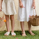 The Olli Ella Rattan Tulip Carry Basket - Natural holding a dozy Dinkum on a baby changing table