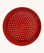 Red metal sand sieve on a cream background