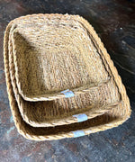 A close up view of the Respiin rectangular seagrass baskets inside eachother on top of a stone surface showing the woven detail.