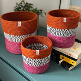 Large and small Respiin jute fire zig zag basket set standing upright on a drawer in a bedroom with the middle basket on top of books