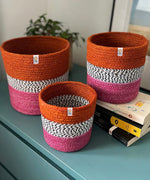 Large and small Respiin jute fire zig zag basket set standing upright on a drawer in a bedroom with the middle basket on top of books