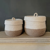 Respiin natural jute lidded basket set in white and natural colourway standing next to each other upright on a stone shelf