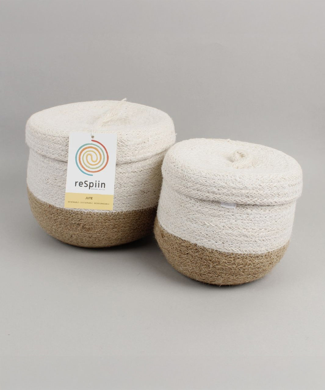 Respiin natural jute lidded basket set. A set of 2 white and natural baskets. Showing the matching white lids on on top and brand tag.