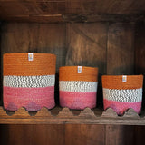 A row of the fire Respiin just fire zig zag baskets standing upright on top of a vintage wooden shelf