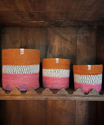 A row of the fire Respiin just fire zig zag baskets standing upright on top of a vintage wooden shelf