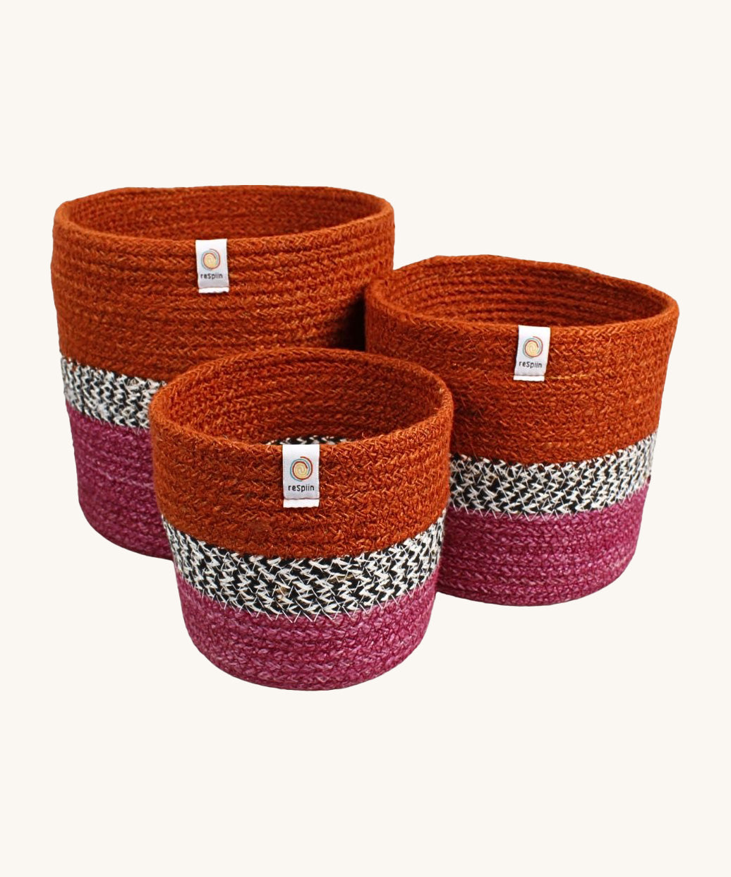 Respiin jute zig zag basket in fire. 3 different sized basket that can fit inside each other. Each basket is  vibrant orange on the top, dark pink on the bottom with a black and white pattern through the middle.