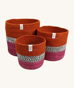 Respiin jute zig zag basket in fire. 3 different sized basket that can fit inside each other. Each basket is  vibrant orange on the top, dark pink on the bottom with a black and white pattern through the middle.