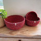 A set of 3 Respiin recycled cotton multicoloured bowls on top of a wooden shelf showing the smaller bowl inside the medium bowl