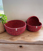 A set of 3 Respiin recycled cotton multicoloured bowls on top of a wooden shelf showing the smaller bowl inside the medium bowl