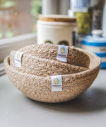 A set of three natural ReSpiin Jute Mini Bowl Set shown nestled inside each other on a window sill