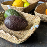 A close up view of the Respiin rectangular seagrass baskets inside eachother on top of a stone surface showing the woven detail and fruit in each basket